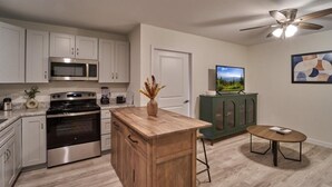 A kitchen with stainless steel appliances, a wooden island, a green cabinet, a small round table, and a ceiling fan. - The Ruby 110 (Pigeon Forge)