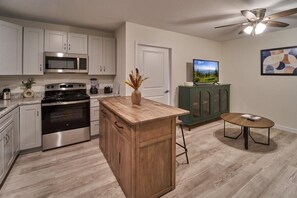 A kitchen with stainless steel appliances, a wooden island, a green cabinet, a small round table, and a ceiling fan. - The Ruby 110 (Pigeon Forge)