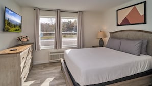 A bedroom with a bed, dresser, lamp, and a painting. - The Ruby 110 (Pigeon Forge)