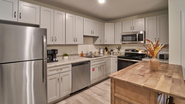 A modern kitchen with stainless steel appliances, white cabinets, and a wooden island. - The Ruby 110 (Pigeon Forge)
