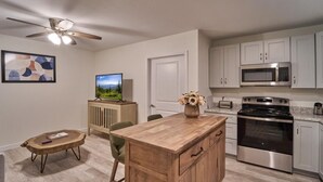 A modern kitchen with a wooden island, stainless steel appliances, and a ceiling fan. - The Ruby 111 (Pigeon Forge)