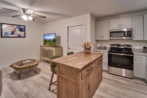 A modern kitchen with a wooden island, stainless steel appliances, and a ceiling fan. - The Ruby 111 (Pigeon Forge)