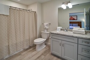 A bathroom with a shower curtain, toilet, sink, and cabinets. - The Ruby 111 (Pigeon Forge)