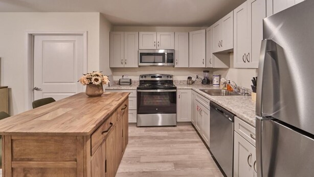 A modern kitchen with white cabinets, stainless steel appliances, and a wooden island. - The Ruby 111 (Pigeon Forge)