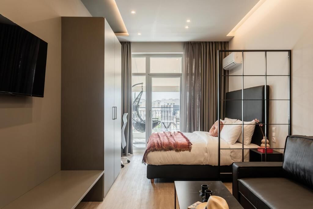 Ein modernes Hotelzimmer mit Bett, Fernseher, Sofa und einem Balkon mit Blick.