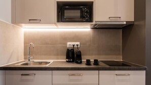 Ett modernt kök med inbyggd mikrovågsugn, kaffebryggare och diskho.