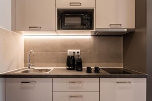 Eine moderne Küche mit integriertem Mikrowellenherd, einer Kaffeemaschine und einem Spülbecken.