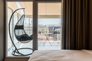 A hotel room with a bed, a hanging chair, and a balcony with a table and chairs. - Au Piree by Calon (Pireas)