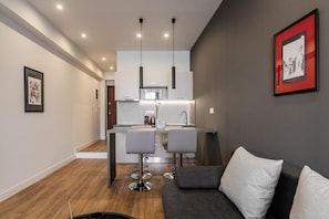A modern kitchen with pendant lights, a central island, and bar stools. - Au Piree by Calon (Pireas)