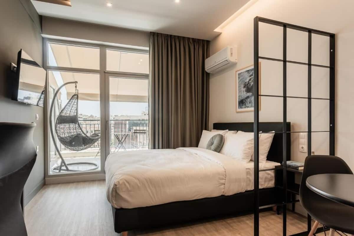 Une chambre d’hôtel moderne équipée d’un lit, d’une chaise, d’un bureau, d’une grande fenêtre et offrant une vue sur la ville.