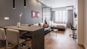 Ett modernt hotellrum med en matplats, en soffa, en säng och ett skrivbord.