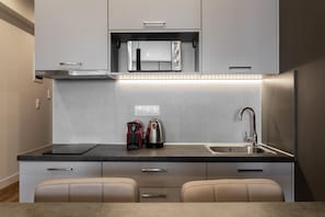 A compact kitchen with a microwave, kettle, and sink. - Au Piree by Calon (Pireas)