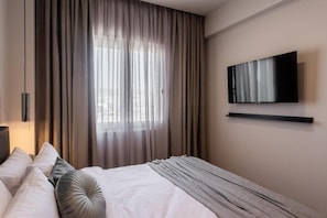 A hotel room with a bed, curtains, a mounted TV, and a bedside table. - Au Piree by Calon (Pireas)