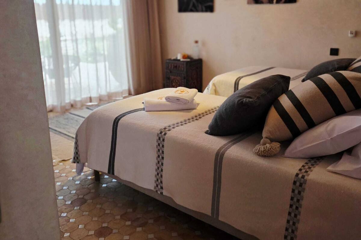 A hotel room with a bed, a nightstand, and a window with curtains.