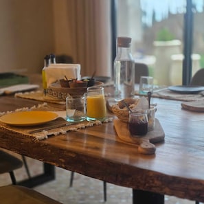 A breakfast table with a plate, glass, and a bottle.