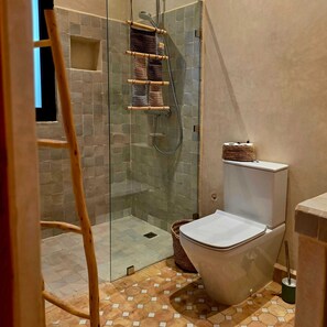 Un baño con ducha de vidrio, inodoro y escalera de madera.