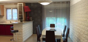A kitchen with a dining area, a red lamp, and a window with blinds. - Holiday Home 'Gîte À Proximité De Blois Chambord' with Private Terrace, Private Garden and Wi-Fi (Les Montils)