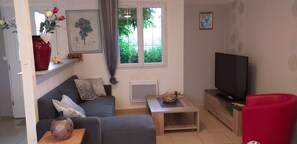 Uma sala de estar com sofá, mesa de centro, televisão e uma cadeira vermelha.