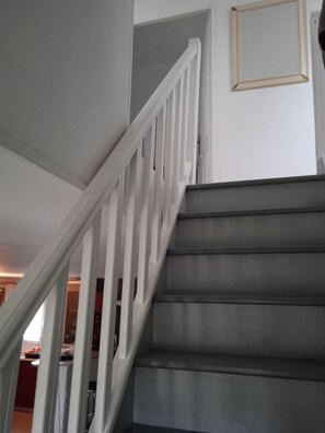 A staircase with white railings and dark steps, leading to a room with a door and a framed picture on the wall. - Holiday Home 'Gîte À Proximité De Blois Chambord' with Private Terrace, Private Garden and Wi-Fi (Les Montils)