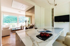 A modern kitchen with a marble countertop, a wine glass, and a cutting board with tomatoes. - Suite Prestige - by MyHomeInComo (Como)