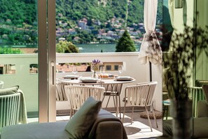 Een balkon met een eettafel gedekt voor vier personen, met uitzicht op een schilderachtig meer en stad.