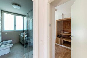 Een moderne badkamer met een glazen douchecabine, toilet en wastafel.