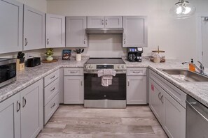 A modern kitchen with stainless steel appliances, white cabinets, and a granite countertop. - The Ruby 114 (Pigeon Forge)