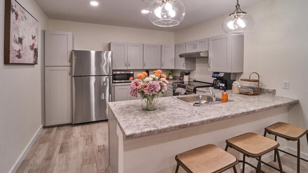A modern kitchen with stainless steel appliances, a granite countertop, and bar stools. - The Ruby 114 (Pigeon Forge)