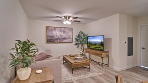 A living room with a sofa, coffee table, TV, and a ceiling fan. - The Ruby 114 (Pigeon Forge)