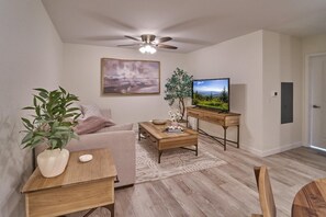 Ein Wohnzimmer mit Sofa, Couchtisch, Fernseher und Deckenventilator.