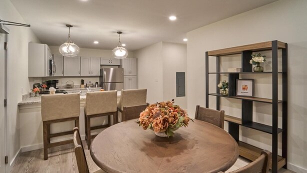 A modern kitchen with white cabinets, a dining table with chairs, and a decorative vase on the table. - The Ruby 115 (Pigeon Forge)