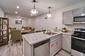 A modern kitchen with granite countertops, stainless steel appliances, and pendant lighting. - The Ruby 200 (Pigeon Forge)