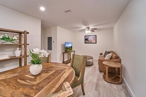 A dining area with a wooden table, chairs, a ceiling fan, a television, and a sofa. - The Ruby 200 (Pigeon Forge)