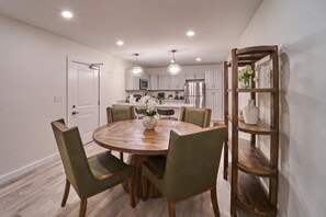A modern kitchen with a round dining table, green chairs, and a wooden sideboard. - The Ruby 200 (Pigeon Forge)