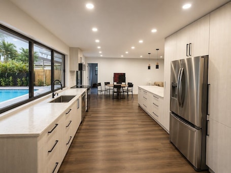 A modern kitchen with a large island, stainless steel appliances, and a view of a swimming pool.. 5BR/3Bath Pool Oasis - Sleeps 10 - 17 Min to Hard Rock Stadium