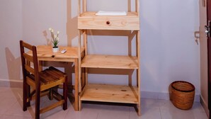 Een kamer met een stapelbed, een houten bureau met stoel, een kleine plant in pot en een mand.