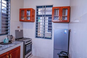 A kitchen with a gas stove, oven, refrigerator, and wooden cabinets.