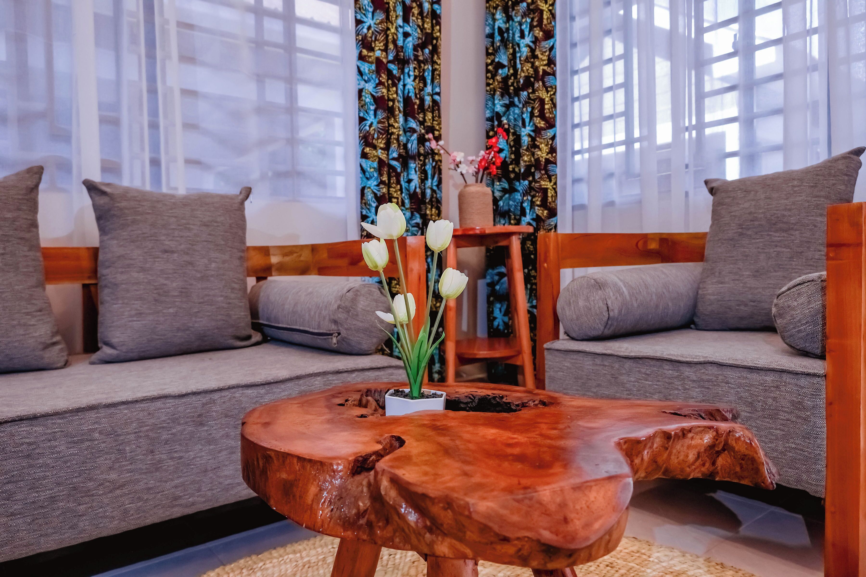 Un salon moderne avec une table basse en bois, un canapé gris et un vase rempli de fleurs blanches.