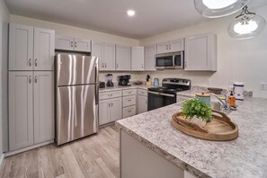 A modern kitchen with stainless steel appliances, a granite countertop, and a built-in microwave. - The Ruby 201 (Pigeon Forge)