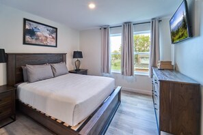 A bedroom with a bed, nightstands, a dresser, a TV, and a window with curtains. - The Ruby 201 (Pigeon Forge)