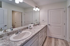 Un bagno con due lavandini, uno specchio grande e una porta.