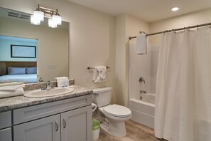 A bathroom with a sink, toilet, bathtub, and shower curtain. - The Ruby 202 (Pigeon Forge)