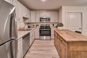 A modern kitchen with stainless steel appliances, white cabinets, and a wooden island. - The Ruby 202 (Pigeon Forge)