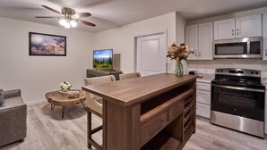 A modern kitchen with a wooden island, stainless steel appliances, and a ceiling fan. - The Ruby 203 (Pigeon Forge)