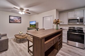 A modern kitchen with a wooden island, stainless steel appliances, and a ceiling fan. - The Ruby 203 (Pigeon Forge)