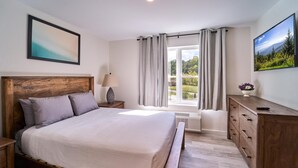 Un dormitorio con cama de madera, una mesita de noche, un aparador, una ventana con cortinas y un cuadro en la pared.