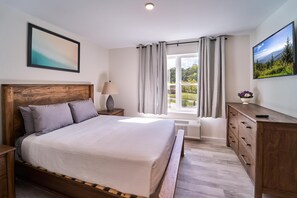 Une chambre à coucher avec un lit en bois, une table de chevet, une commode, une fenêtre avec des rideaux et un tableau au mur.