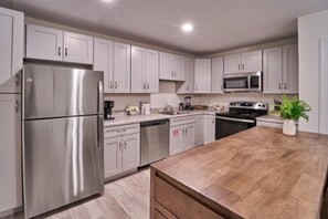 A modern kitchen with stainless steel appliances, white cabinetry, and a wooden countertop. - The Ruby 206 (Pigeon Forge)