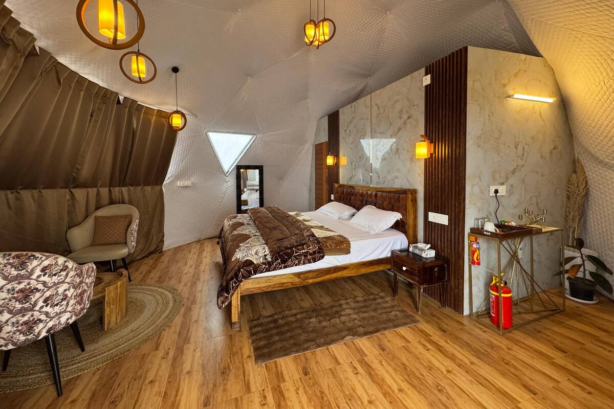 Une chambre aménagée comme une tente, avec un lit, un coin salon et une petite table.