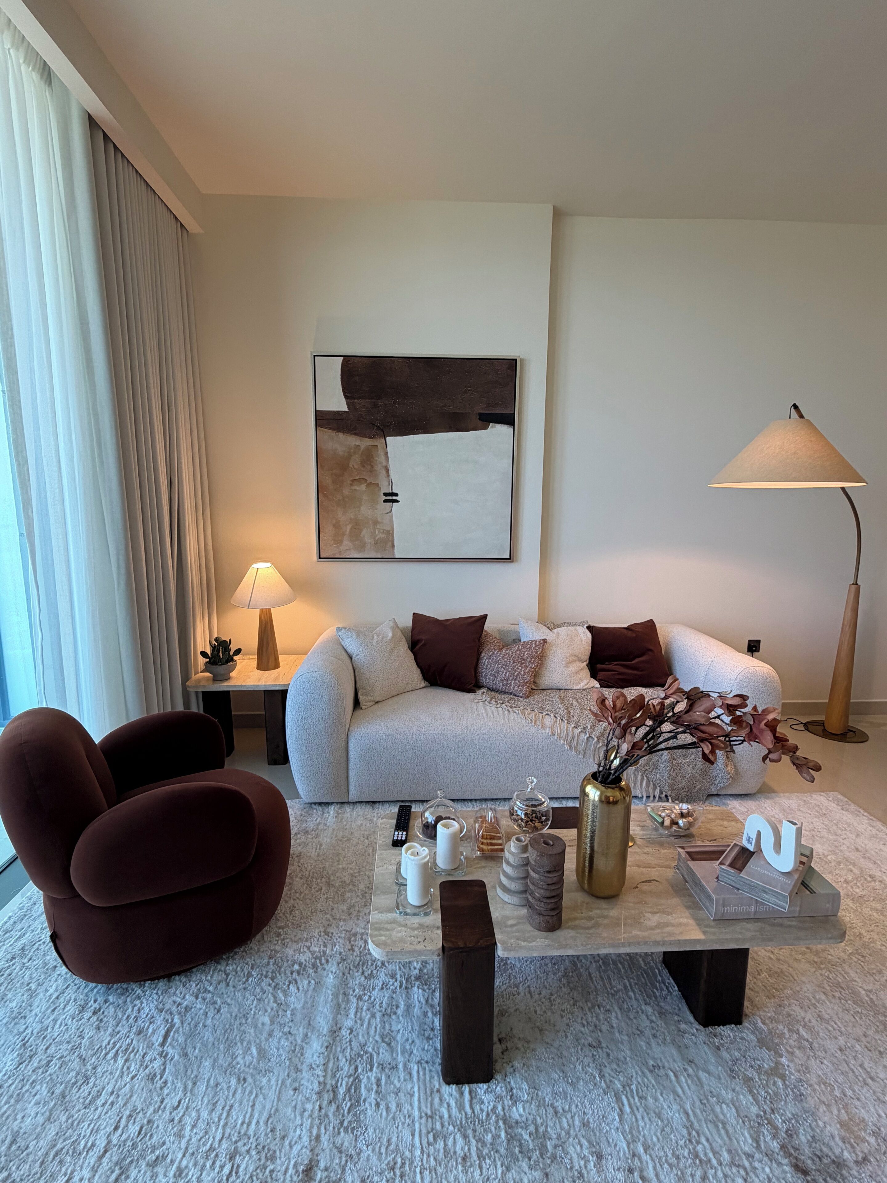 A modern living room with a sofa, a coffee table, a lamp, and a painting on the wall.
